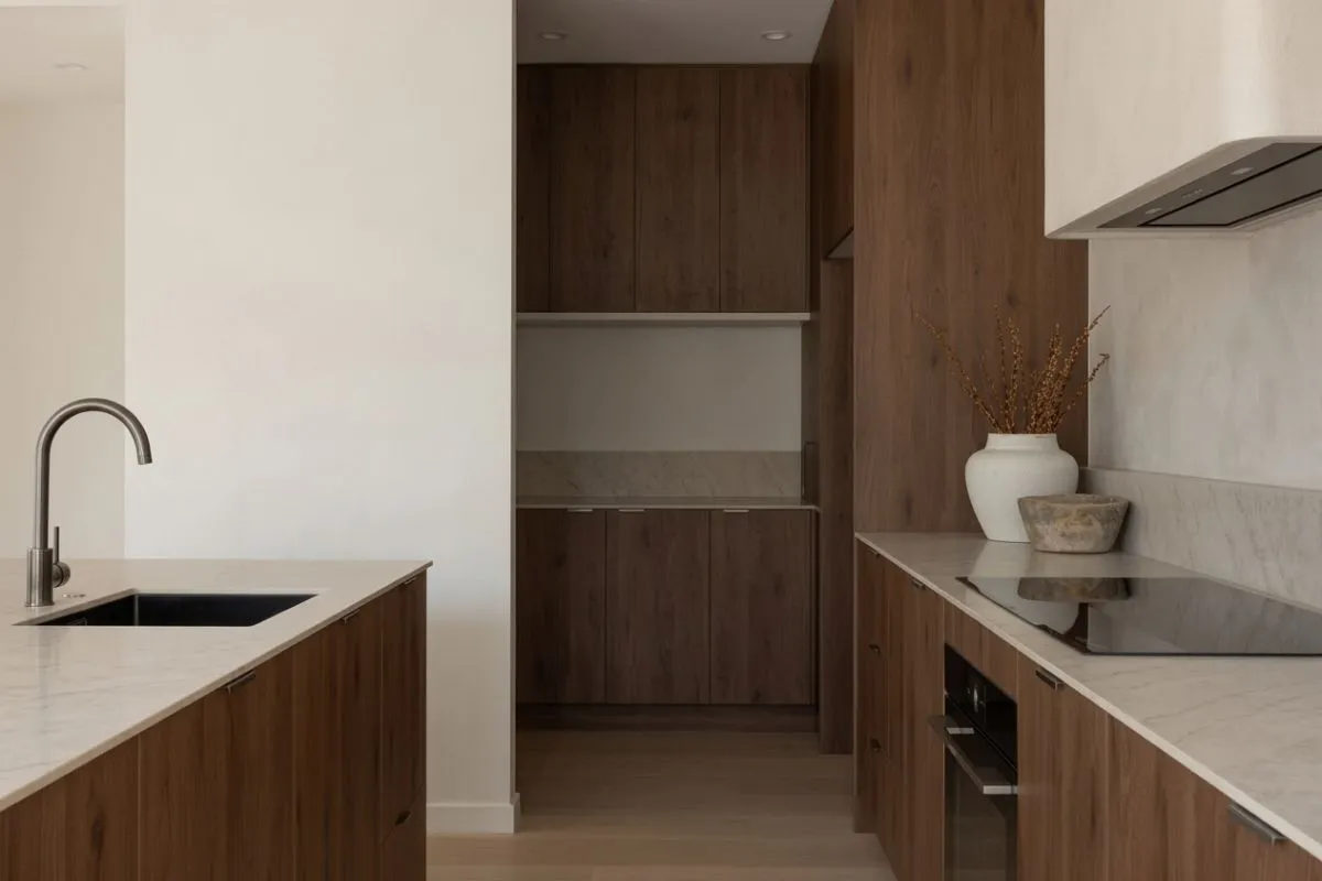 Cocina a medida en roble con mesada de mármol blanco y despensa integrada